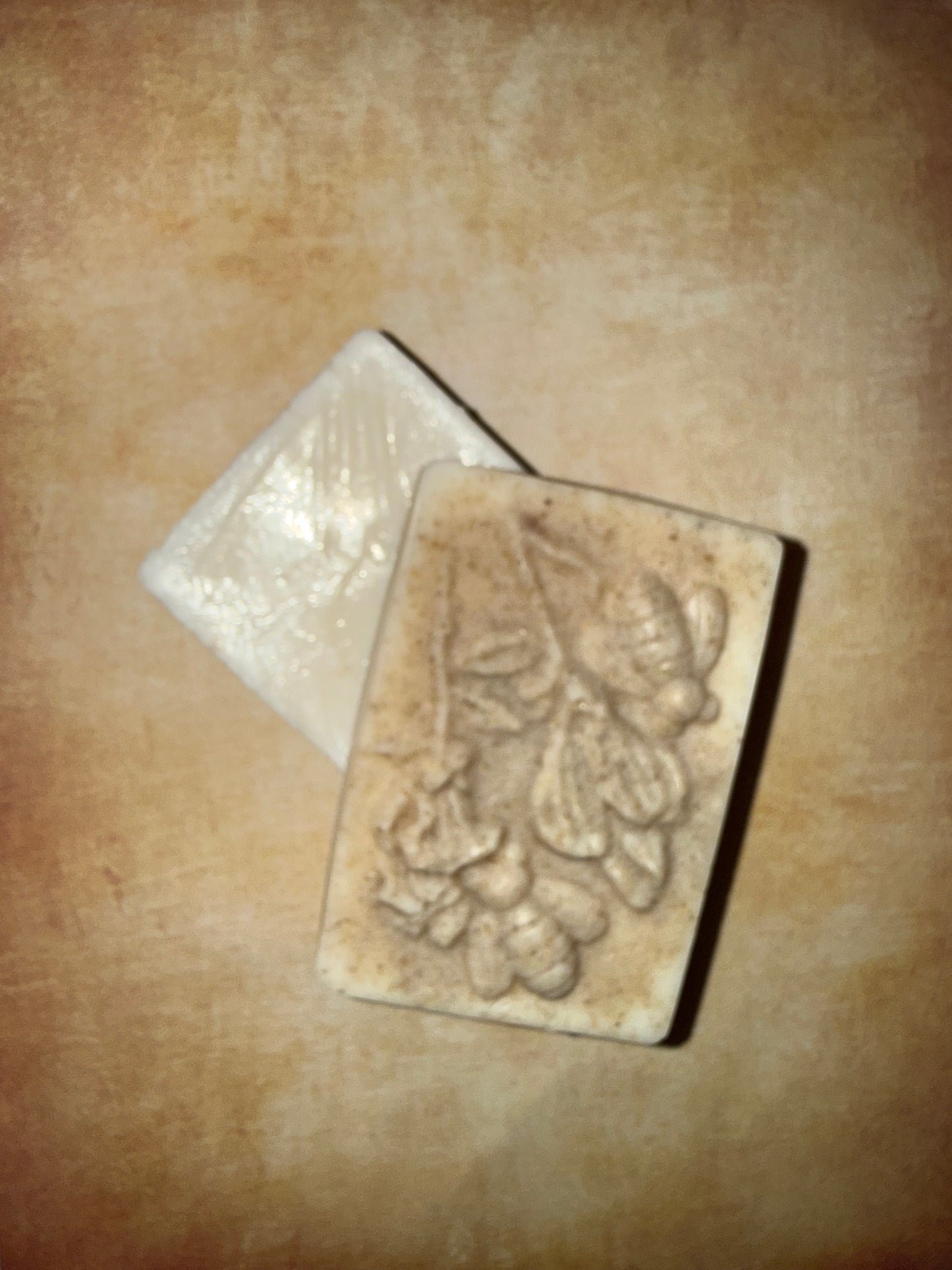 Two soap bars with floral designs on a beige surface