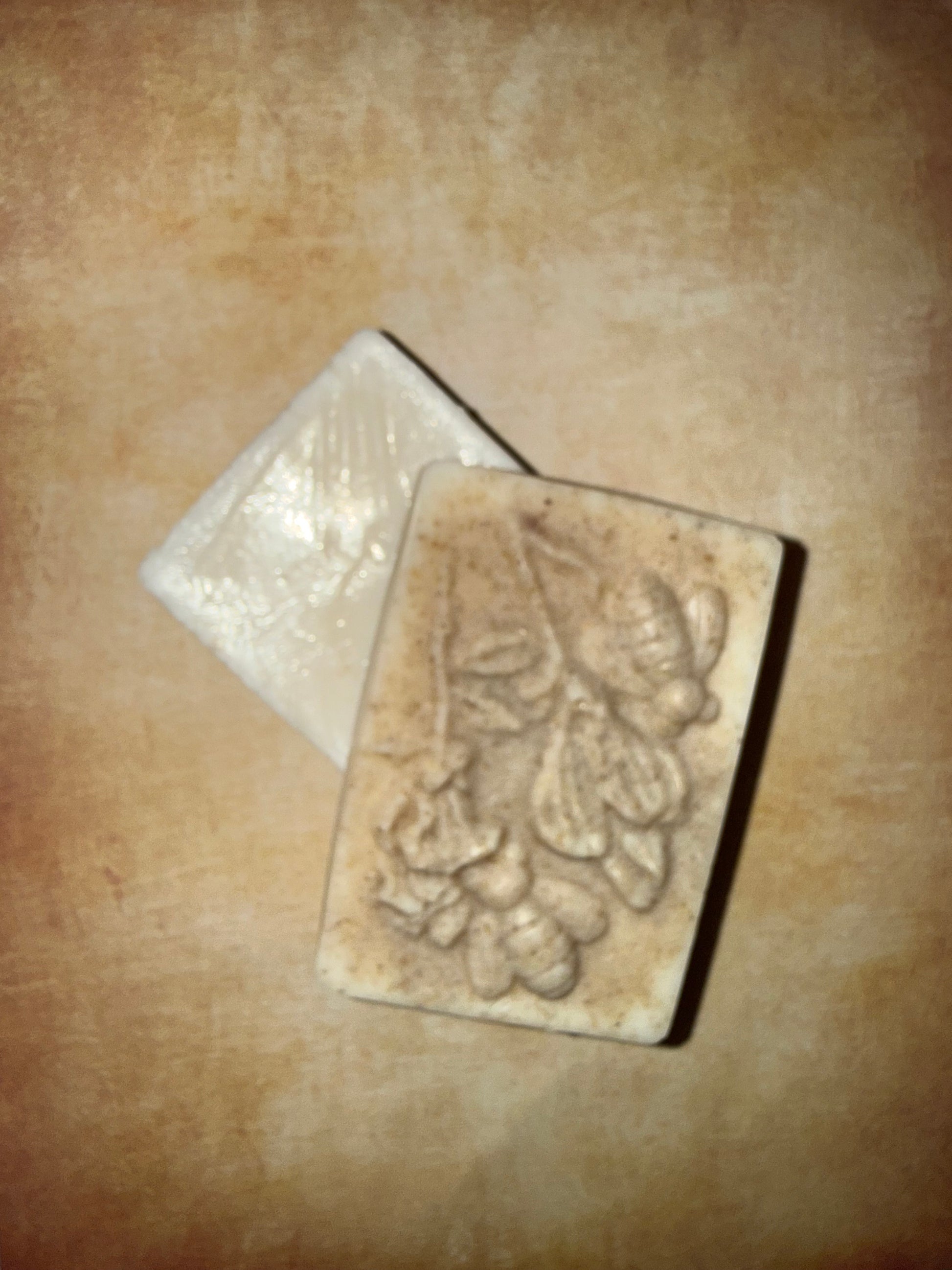 Two soap bars with floral designs on a beige surface